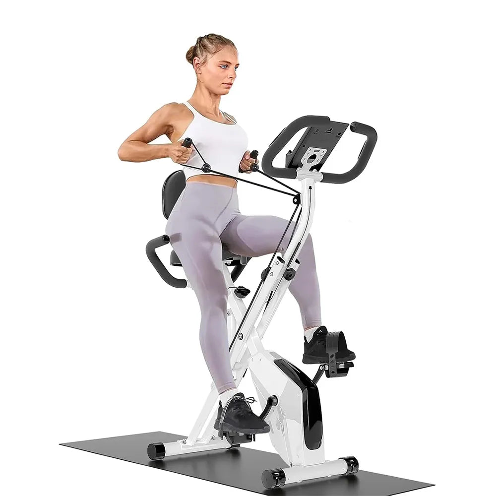 A woman exercising on a white and black indoor Elarvo Foldable Exercise Bike with resistance handles, shown against a plain white background.