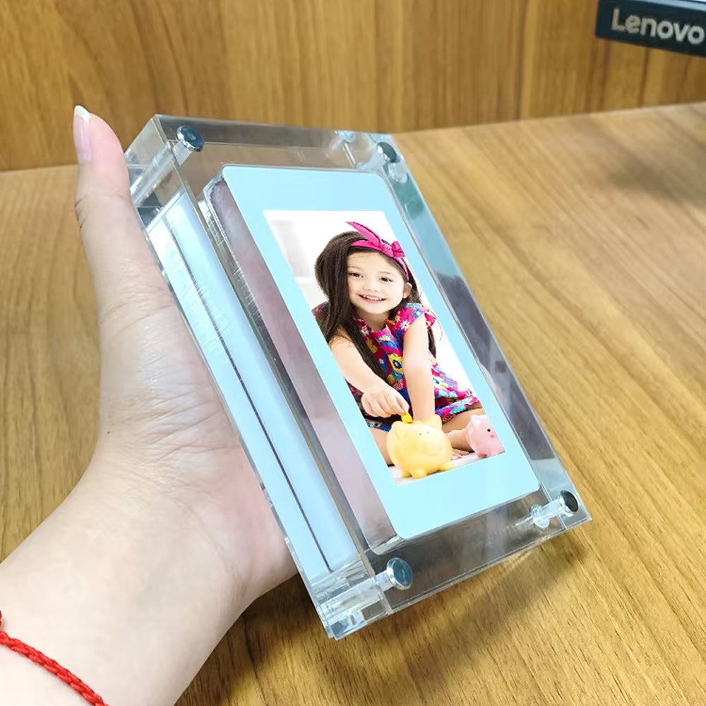 Hand holding a transparent electronic device displaying a CaptiPix Digital Photo Frame of a child on a wooden surface.