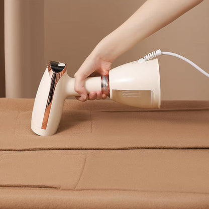Hand holding a white CriisMist Handheld Steamer cleaner on a brown surface.