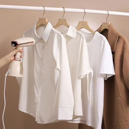 White shirts on hangers with a hand holding a CriisMist Handheld Steamer against a beige background