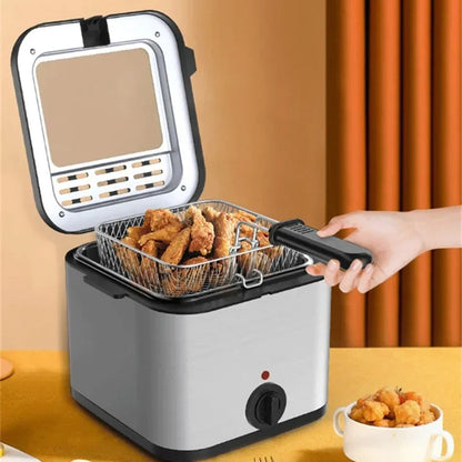 A countertop electric deep CryspiPro Fryer with its lid open, showing a wire basket filled with golden fried food. A hand is holding the basket handle, and a small cup of fried food sits on the table beside it.