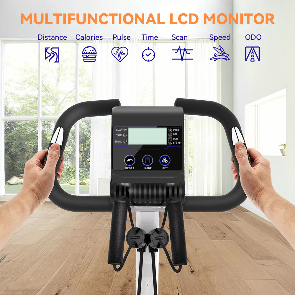 A black multifunctional LCD monitor Elarvo Foldable Exercise Bike with a digital display screen and control buttons, held by two hands in front of a windowed wall and wooden floor. Orange text at the top reads 'MULTIFUNCTIONAL LCD MONITOR' with blue feature icons above.