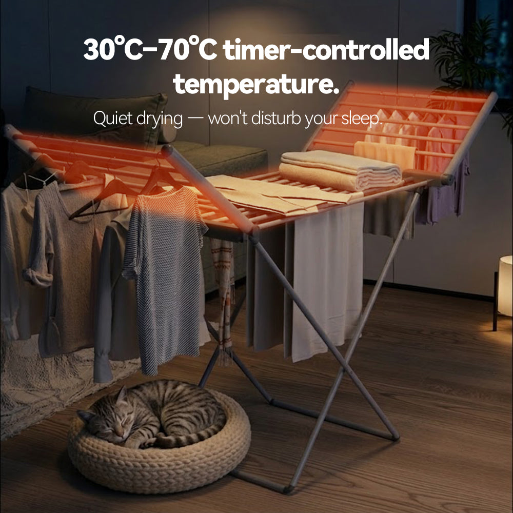A freestanding Elarvo Heated Clothes Airer drying rack with orange support bars and hanging garments, shown in a styled bedroom scene. A cat is sleeping in a woven basket on the floor below.