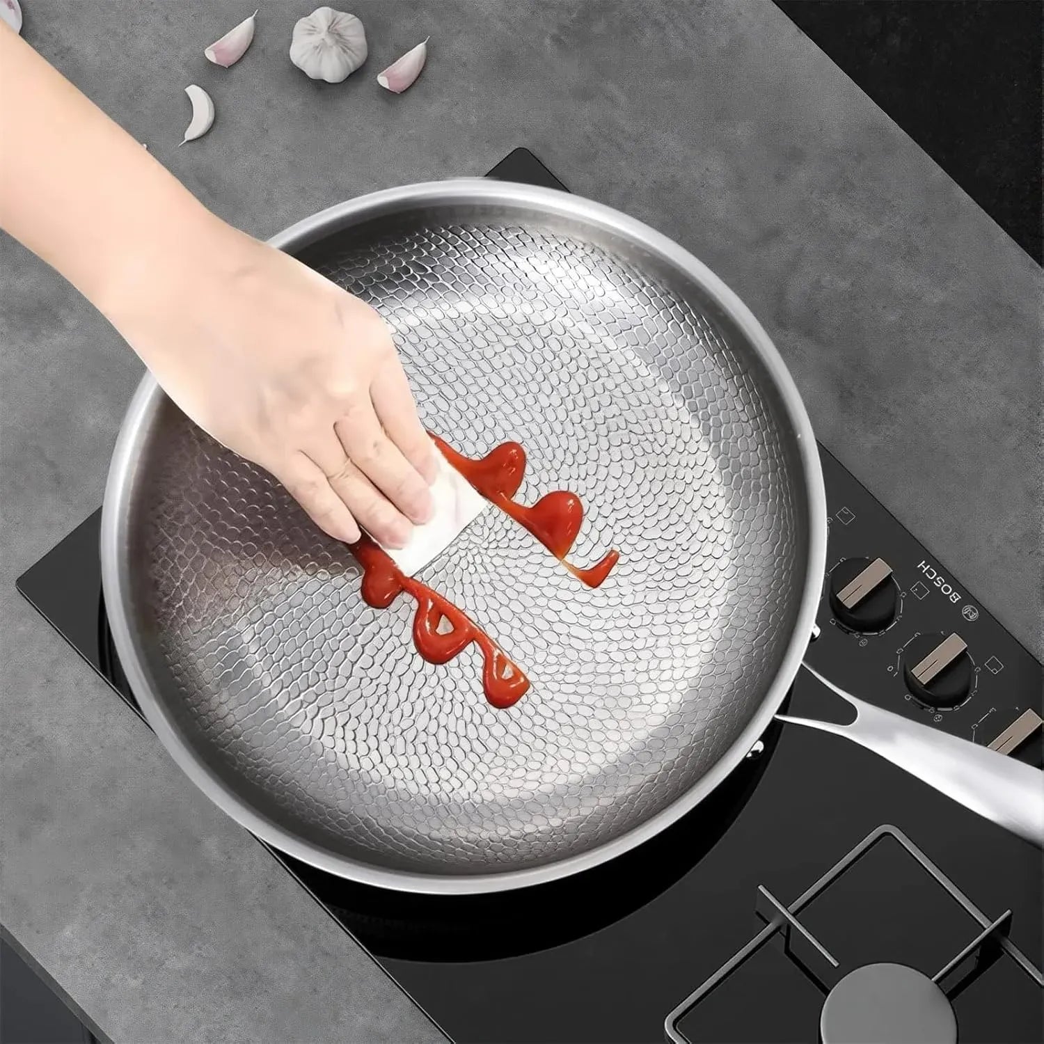Person using a knife to spread red sauce on a non-stick Ironis Titanium Hammered Pan.