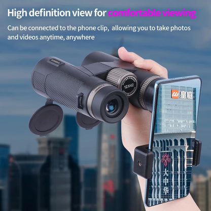 Hand holding Kaisio Sky X7 ED 12×50 Binoculars with a phone clip attached, cityscape in the background