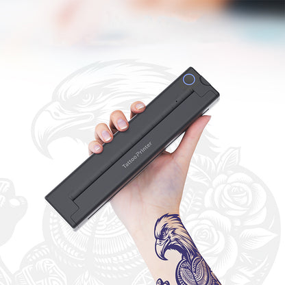 Hand holding a Keovy Tattoo Printer with a tattoo on a blurred background