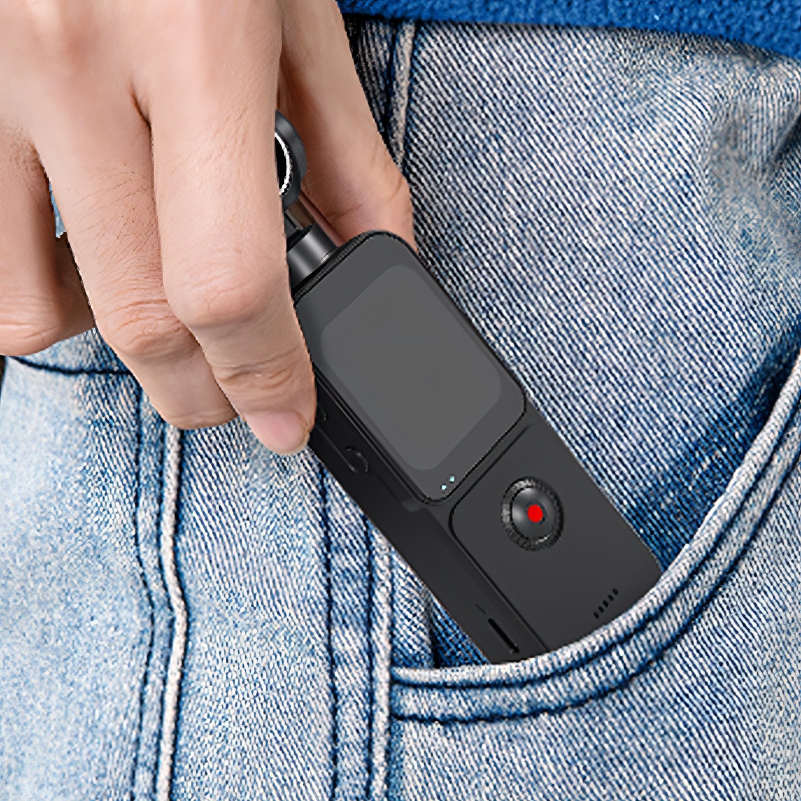 Hand inserting a small black Keovy Vlogging Camera into a blue denim pocket