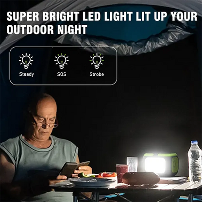Person using a smartphone at a table with a bright light source in the dark, highlighting LED light features MQPower Portable Power Stations