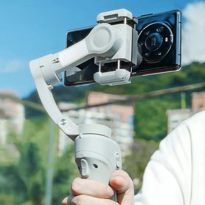 Hand holding a smartphone Optego Gimbal with a clear sky and blurred background