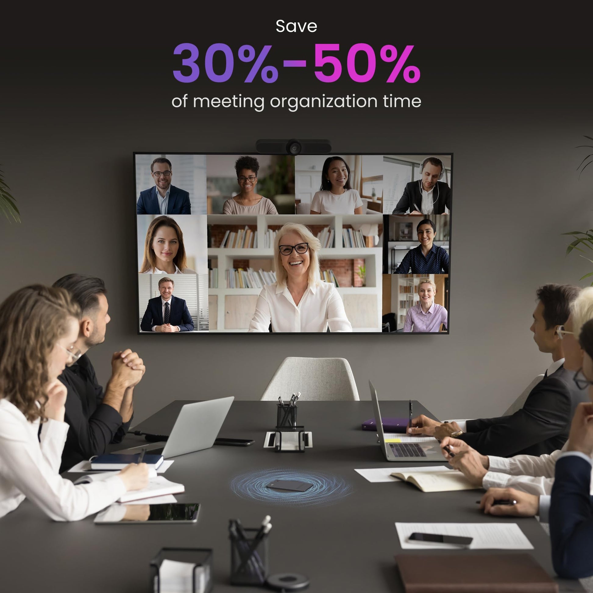 Group of people in a video conference call with a screen displaying multiple participants, set against a dark wall.