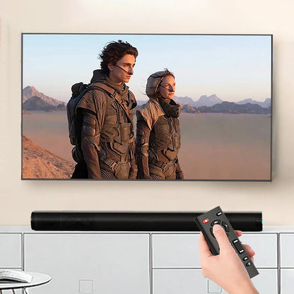 Person holding a remote control in front of a TV displaying two people in futuristic outfits.