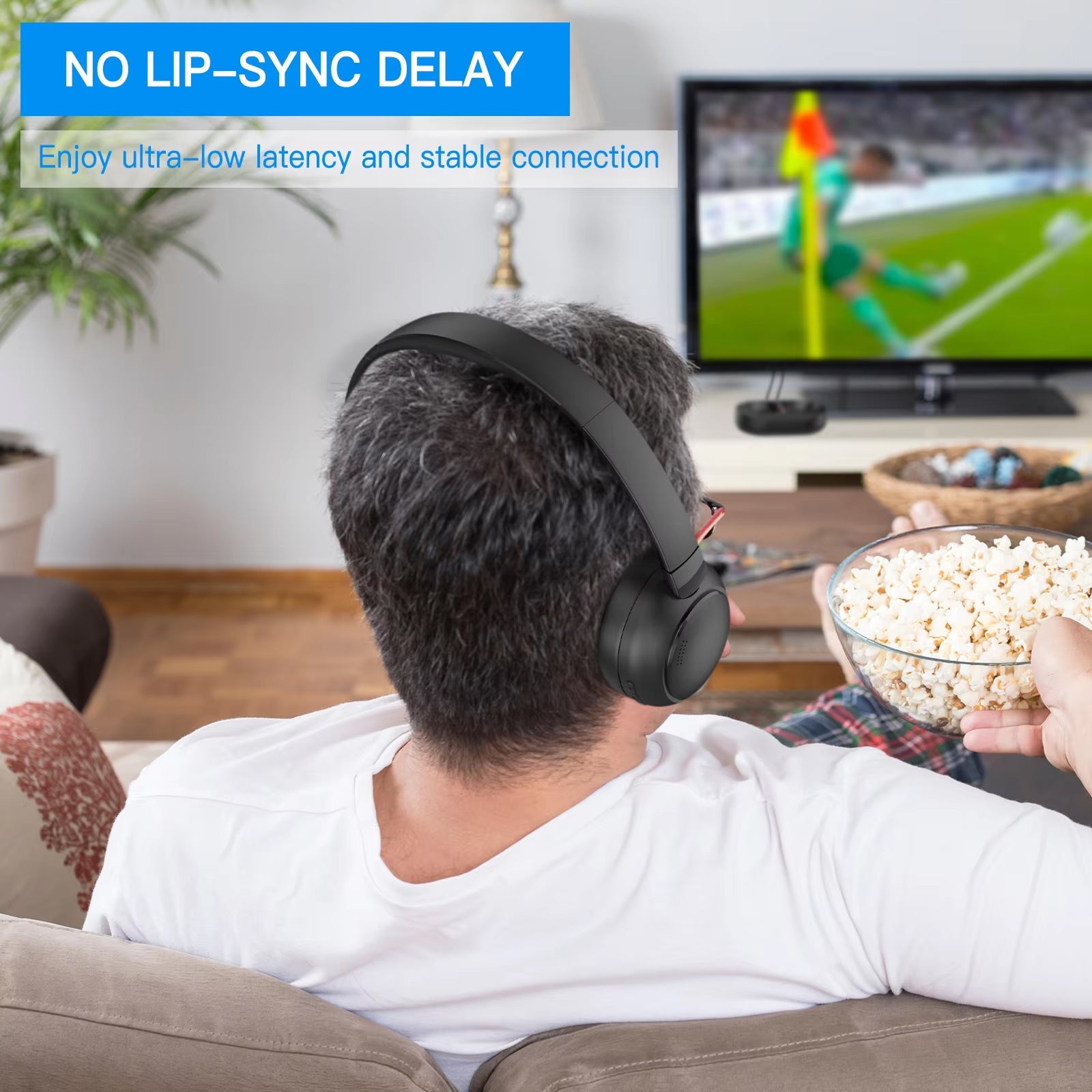 Person wearing Sintra TV Headphones and eating popcorn while watching TV in a living room.