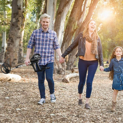Man, woman, and child walking together in a park with trees and sunlight.