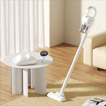 White handheld VaciMatri Mattress Vacuum Cleaner on a carpeted floor with a table and curtains in the background.