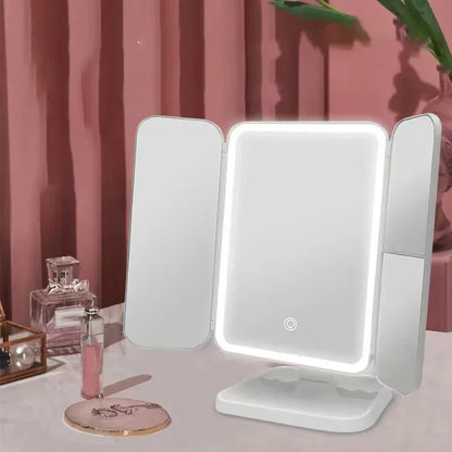 Tri-fold VeloGleam Lighted Makeup Mirror with LED lights on a pink surface with decorative items.