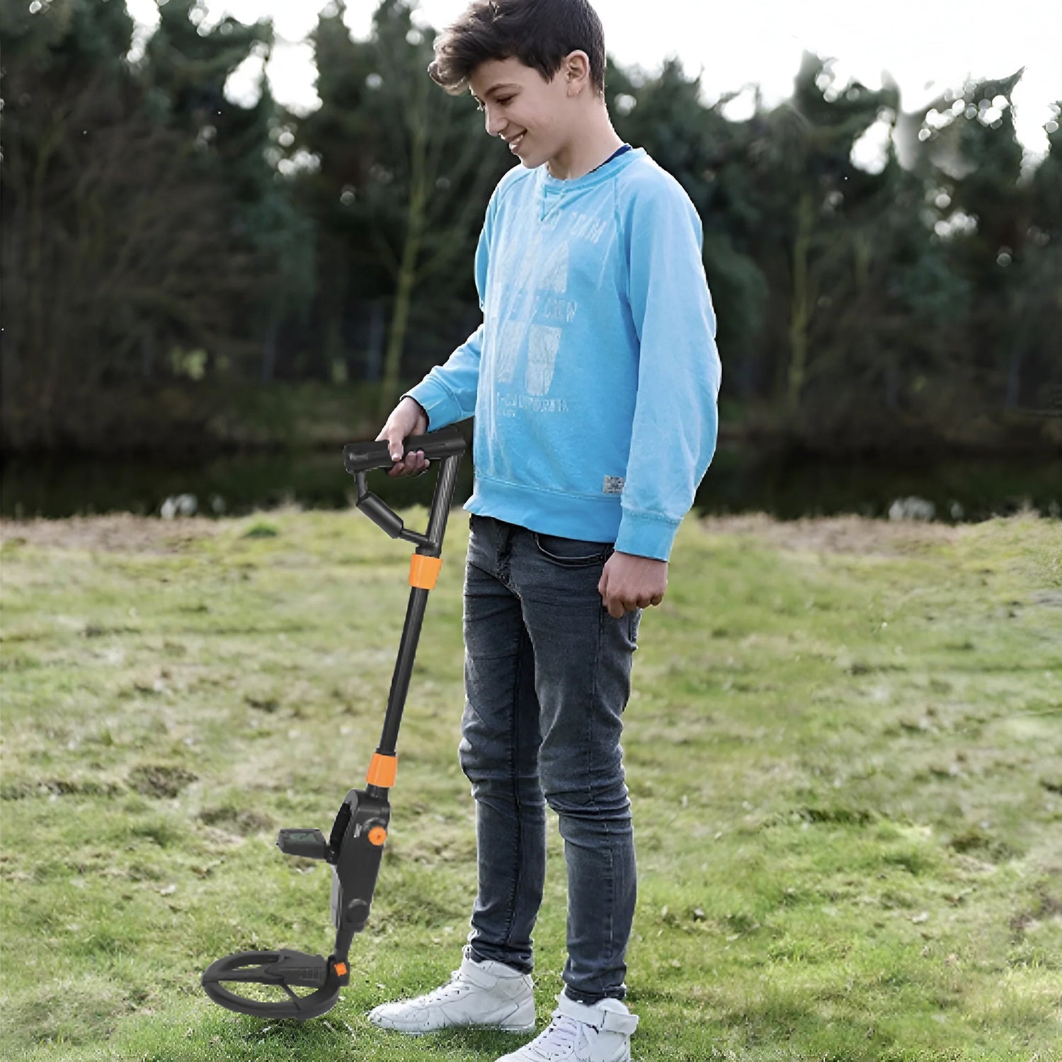 Child holding a Zorby Kid Metal Detector in a grassy field with trees in the background