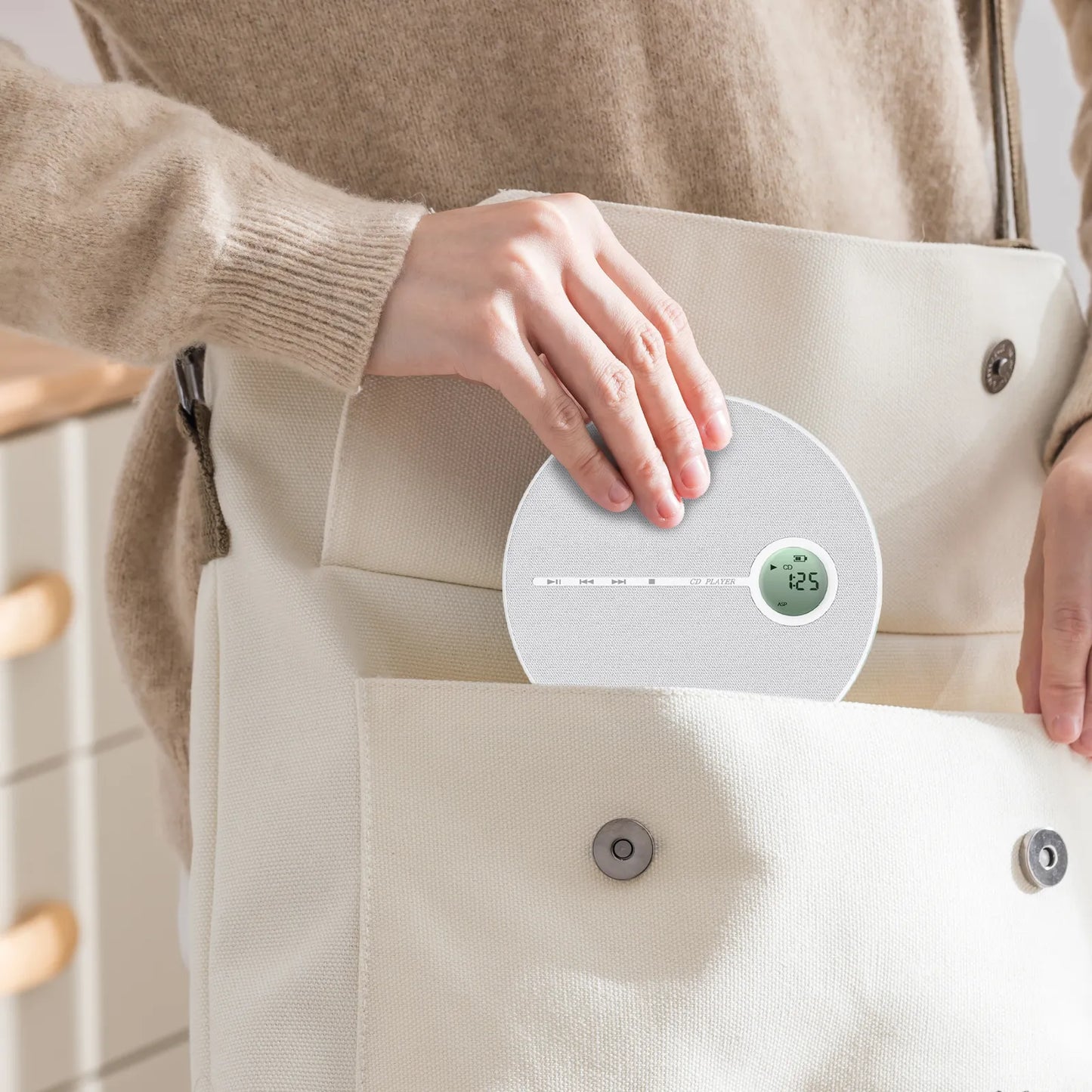 Person holding a digital Valis Portable CD Player against a beige jacket pocket.