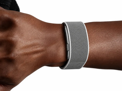 A close-up of a person's wrist wearing a gray textured Ionos Screenless Fitness Tracker with a silver metallic edge, shown against a plain white background.