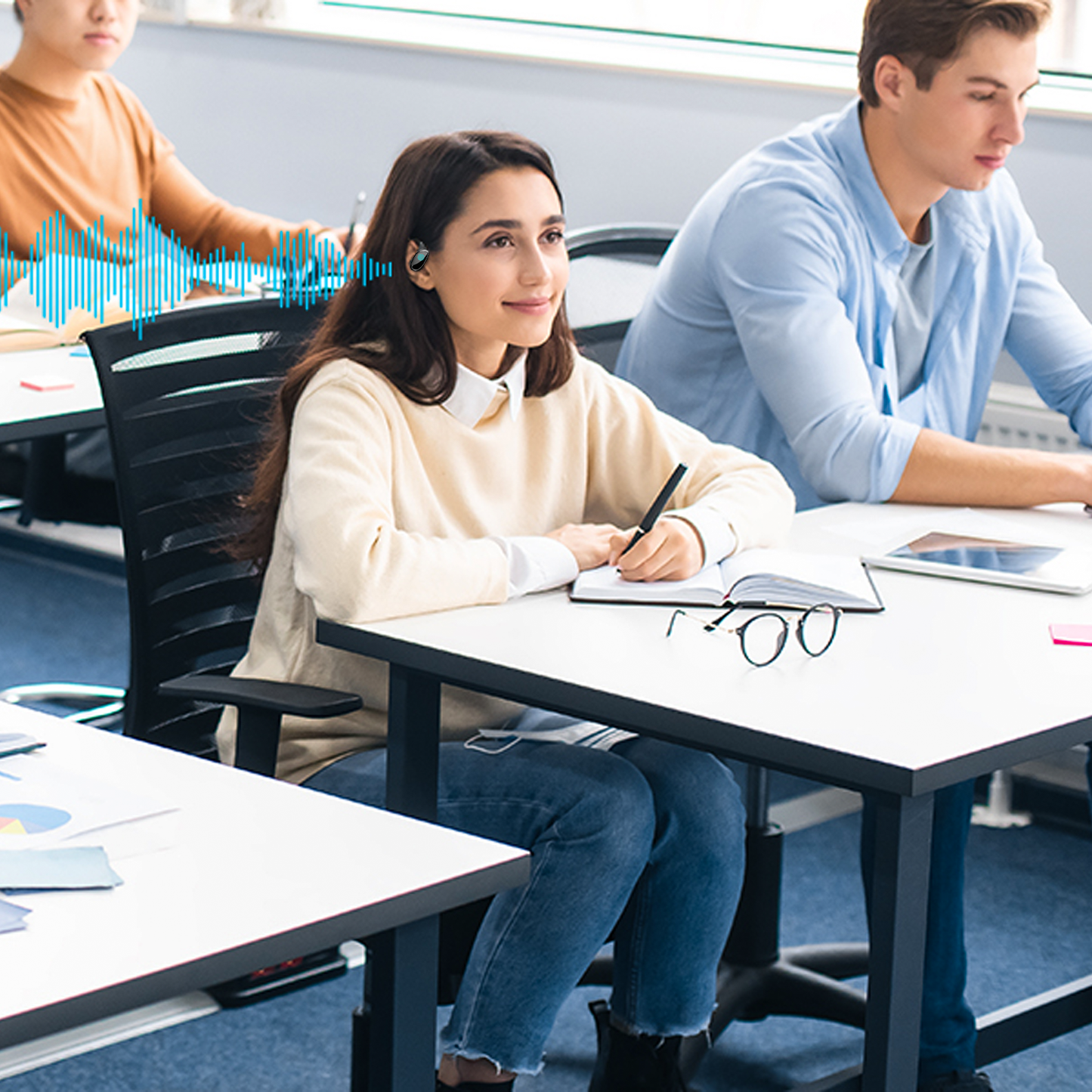 Students in a classroom setting with one student taking notes.