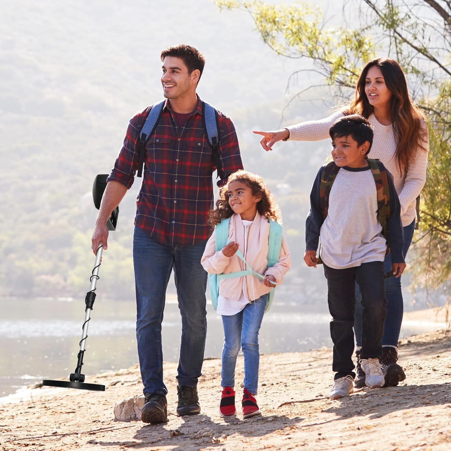 Family of four walking outdoors by a lake with a Trexorax Metal Detector.