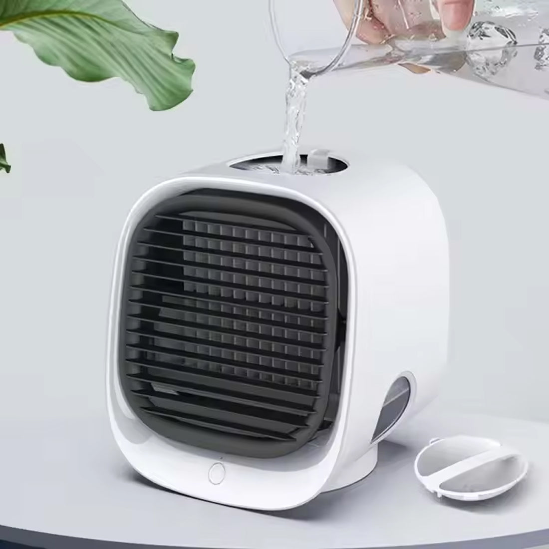 White and black Coolevax Portable Air Conditioner on a light gray surface with a plant leaf in the corner.